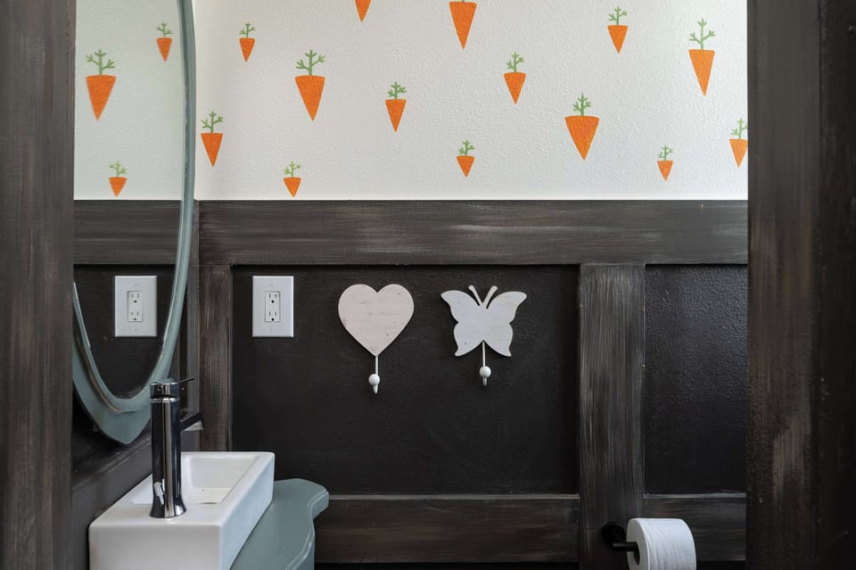 A modern bathroom with playful carrot wall art and dark wood accents.