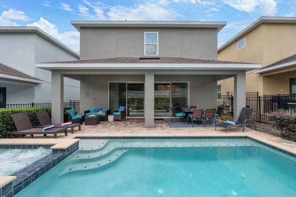 Covered patio with seating and a pool with spa for relaxing outdoor enjoyment