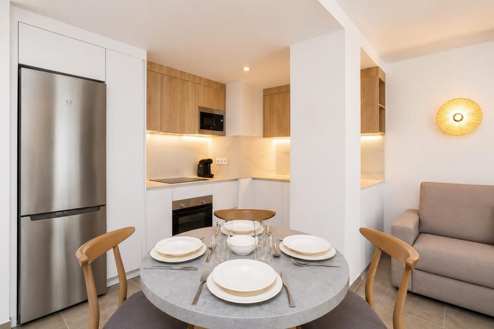 Modern open-plan kitchen and dining area with warm wooden cabinetry and a stylish table setting.