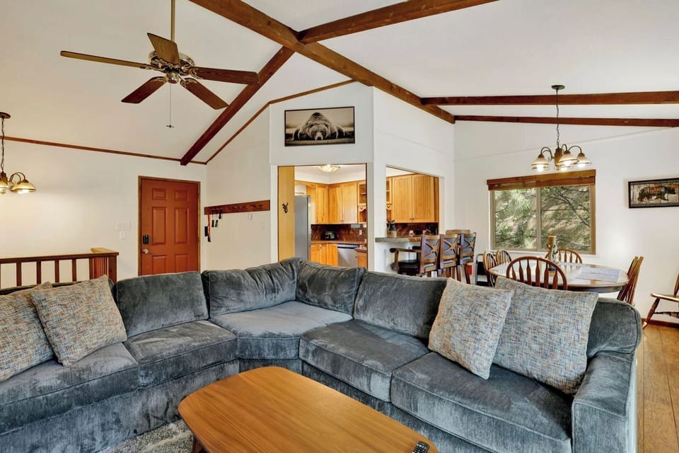 Cozy open living space with vaulted ceilings, beams, and large sectional