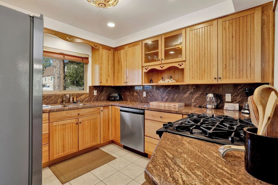 Bright kitchen with granite counters, gas cooktop, and warm wood cabinetry