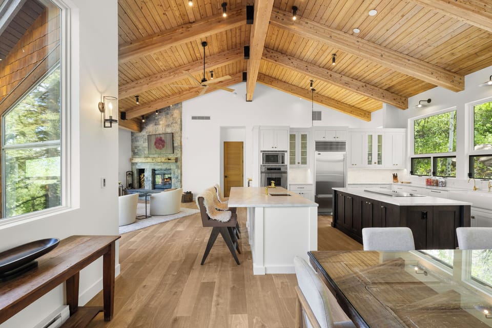 Open concept dining and kitchen with tongue-and-groove ceilings throughout and access to both the back and front deck spaces.