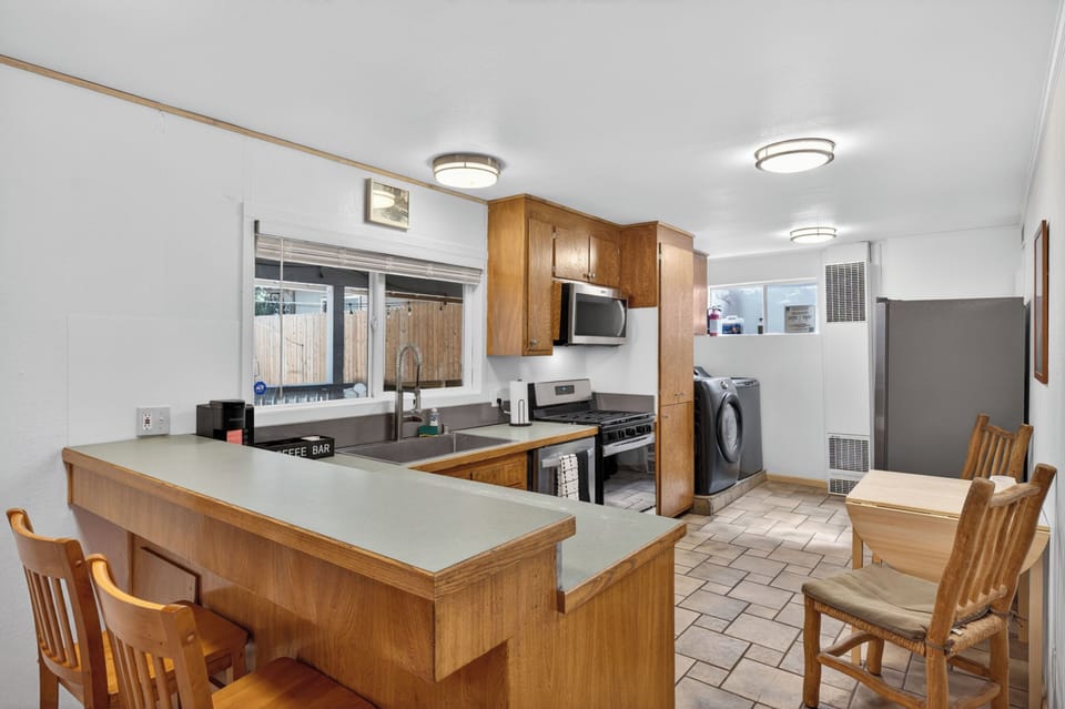 This functional kitchen features warm wood cabinetry, a gas range, and plenty of counter space to cook in during your stay. You will also find the convenient in-unit washer and dryer tucked just off to the side.