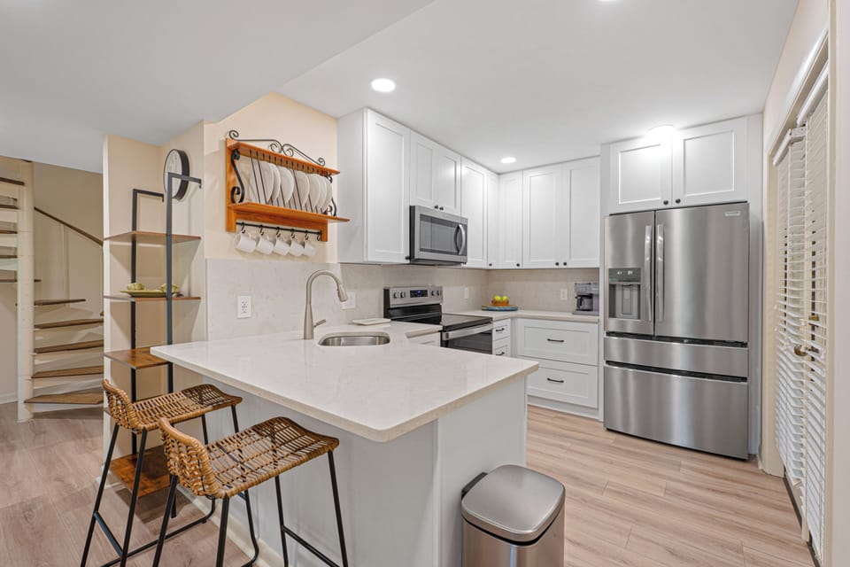 The kitchen is designed to make every meal effortless, featuring quartz countertops, stainless steel appliances, abundant cabinetry, and a spacious breakfast bar.