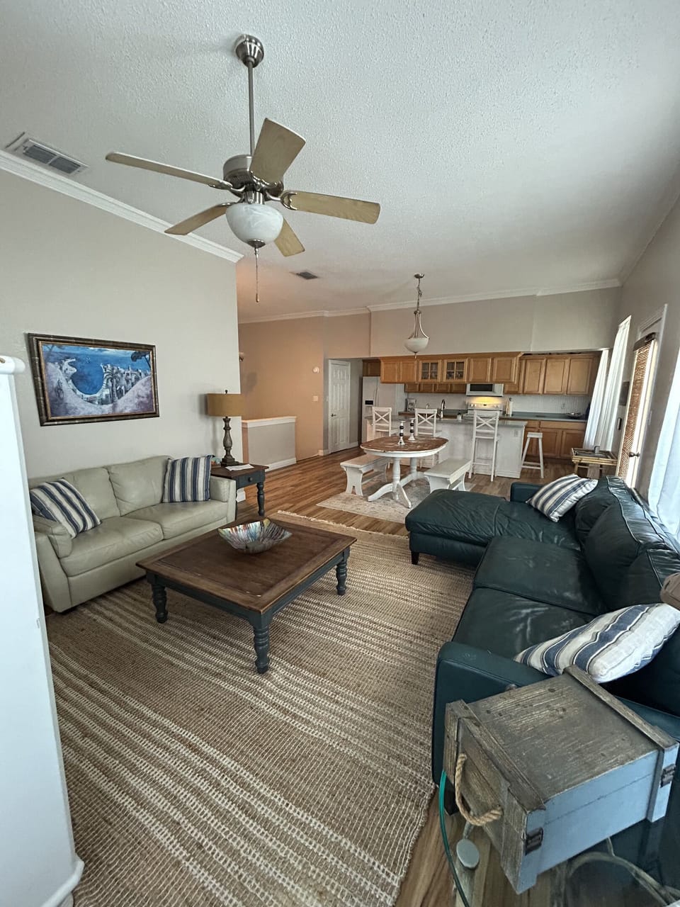 Bright and airy open-concept living space with vaulted ceilings and coastal charm. Relax on plush seating with nautical-inspired accents, enjoy natural light from multiple windows, and take in views of the kitchen and dining areas. 