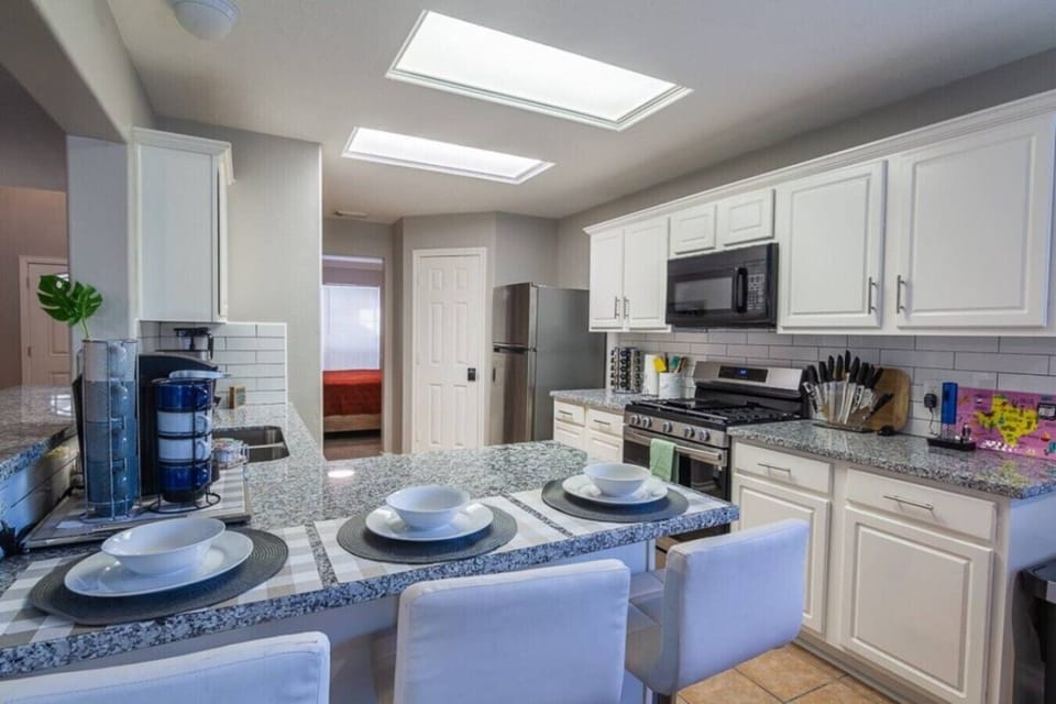 Modern kitchen with granite counters, breakfast bar, and stainless steel appliances.