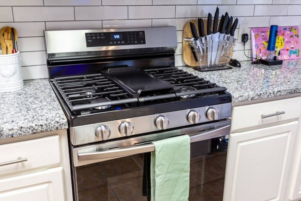 Modern stainless steel gas range with granite counters and knife set.