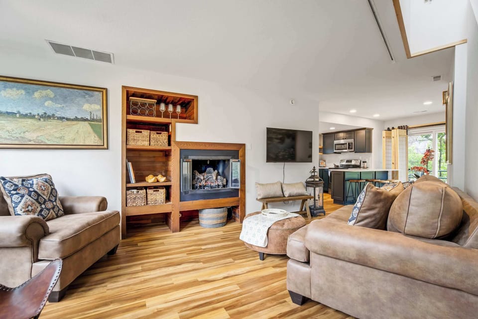 The open layout connects living, dining, and kitchen effortlessly, anchored by the built-in wood bookcase, a wall-mounted TV, and sliding doors that open directly onto the outdoor deck and backyard below.