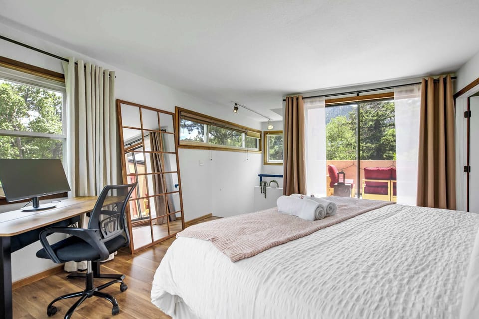 The standing desk, monitor, and ergonomic chair sit beside large windows, with the private balcony just steps away and treetop views that make it easy to find the right balance between work and a proper Colorado escape.
