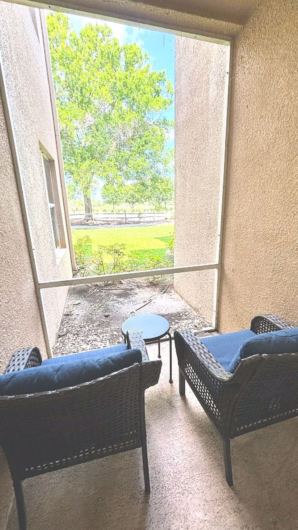 Private screened balcony with outdoor seating and peaceful views of the surrounding green space.