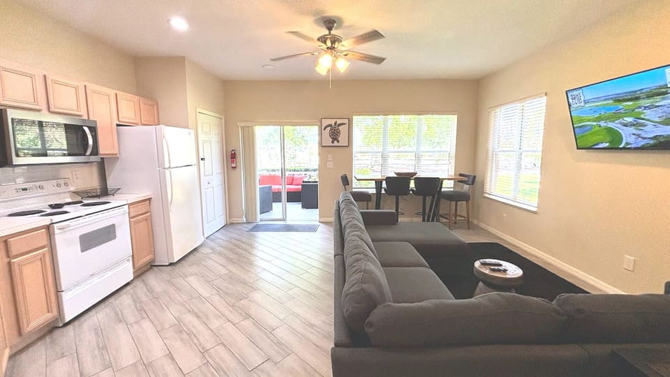 Open kitchen and living area with tile and wood-look flooring, full-size appliances, and easy access to the outdoor space.