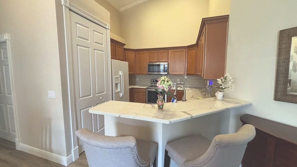The modern kitchen boasts beautiful wood cabinetry, sleek stainless steel appliances, gleaming stone countertops, and a convenient breakfast bar with comfortable seating.