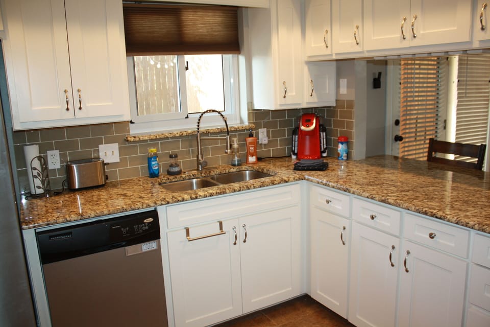 Kitchen sink, coffee maker, toaster and dishwasher. 