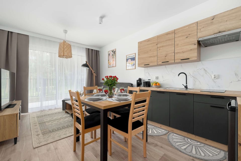 A kitchen and dining area shown from a different angle with a wooden table and chairs. The design emphasizes openness and practical use of space.