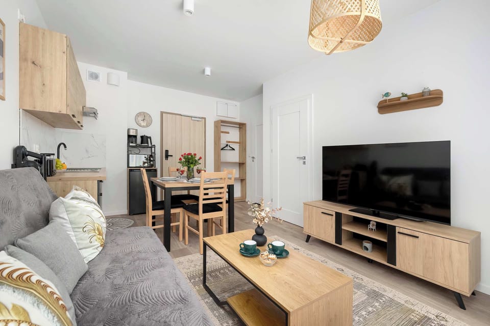 A cozy living room corner with seating and a television. The interior feels modern, simple, and well-organized.