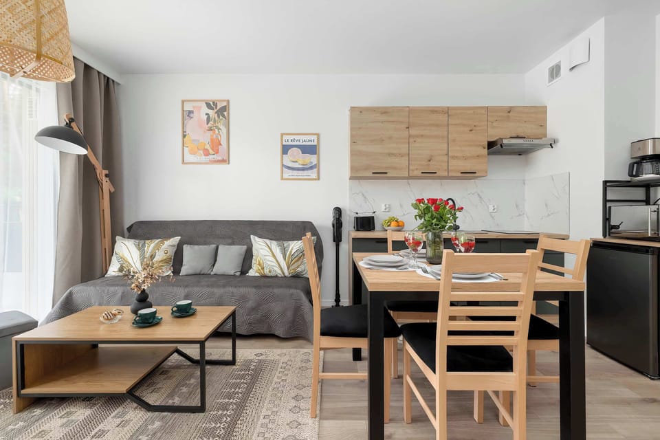 A bright dining and living space combining a wooden table and a cozy seating area. The layout is open and designed for comfortable everyday living and gatherings.