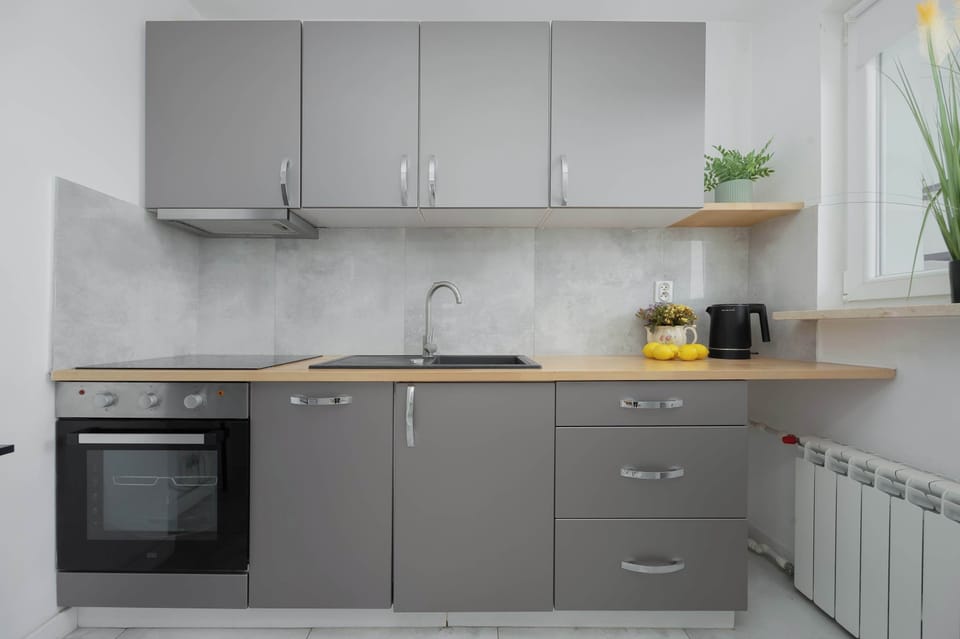 A modern kitchen with gray cabinets, wooden countertops, and built-in appliances. The space is bright and functional.