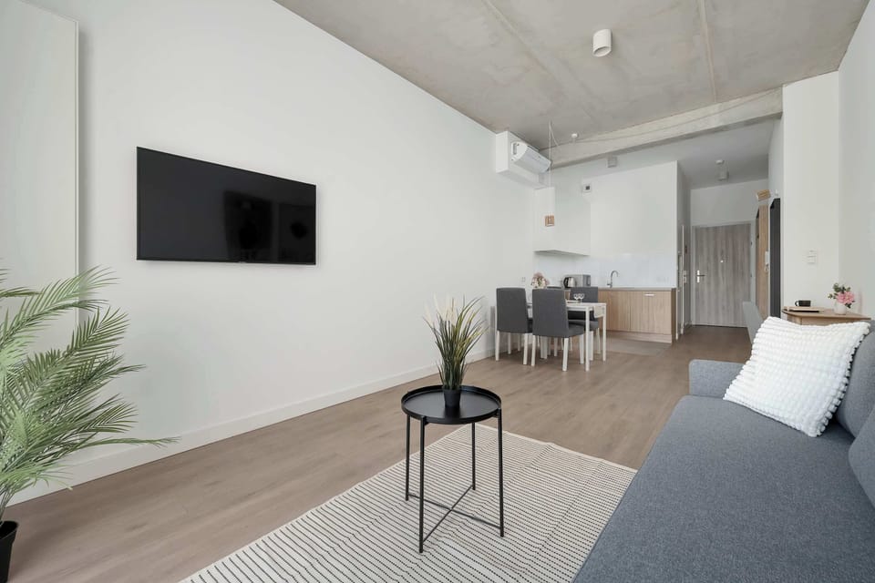 Another angle of the living room highlights the wall-mounted television and open connection to the kitchen. Neutral tones contribute to the contemporary design.