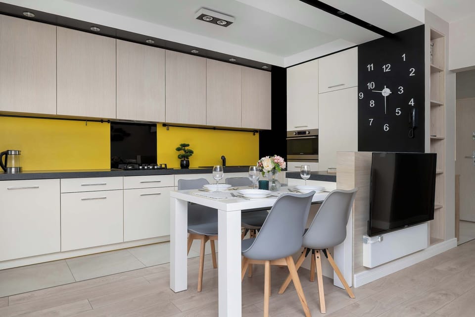 The kitchen counter opens up to the dining table, showing the integration of a flat-screen television built into the cabinetry unit. This multi-functional layout maximizes the use of space in the apartment.
