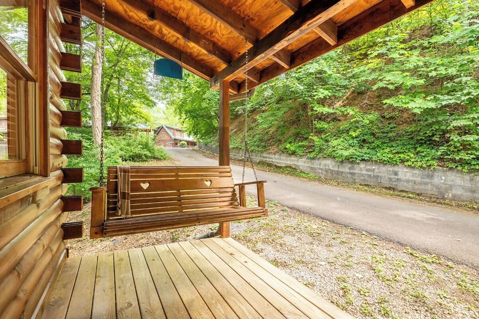 Swing gently on your private covered porch, surrounded by lush greenery and the quiet charm of a peaceful wooded setting.