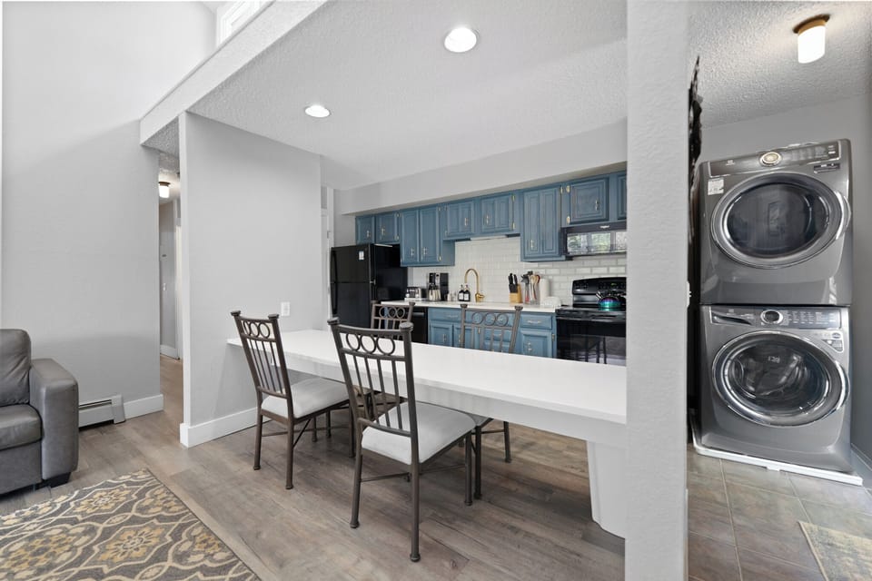 Your open-concept space invites you to cook, dine, and relax with modern blue cabinetry, gleaming countertops, and in-unit laundry tucked conveniently nearby.