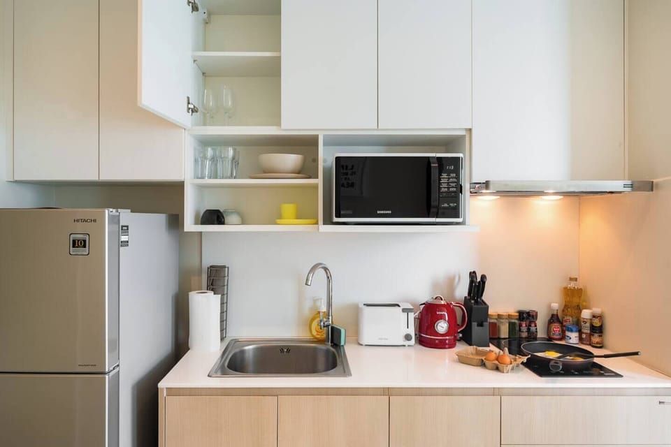 Kitchen equipped with fridge, stove, hood, microwave, kettle and toaster.