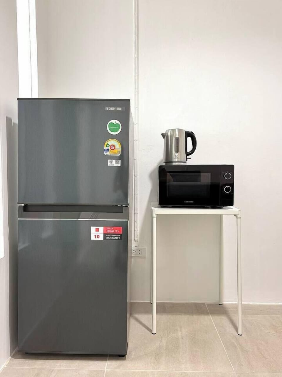 The full-size fridge, microwave, and kettle are included, and there's a dining table nearby so you can easily heat up food and dine comfortably.