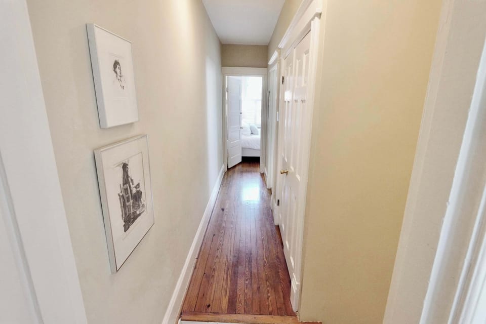 Framed artwork and warm hardwood floors create an elegant transition between the two sleeping areas.