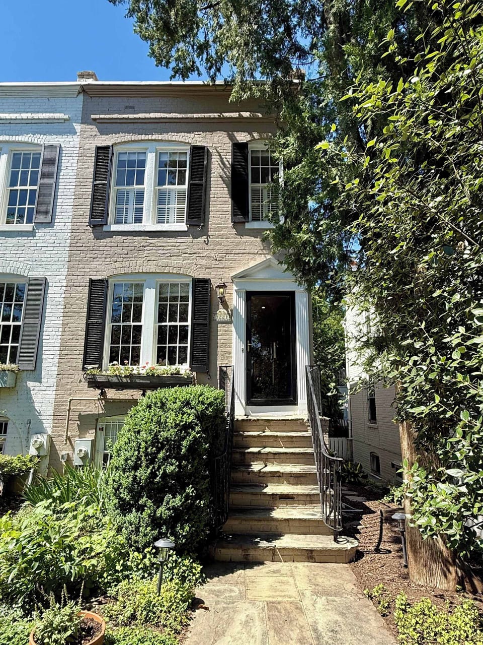 A charming garden pathway leads to the home's private entrance, showcasing timeless architecture and mature landscaping. Please note that stairs are required to access the front door.