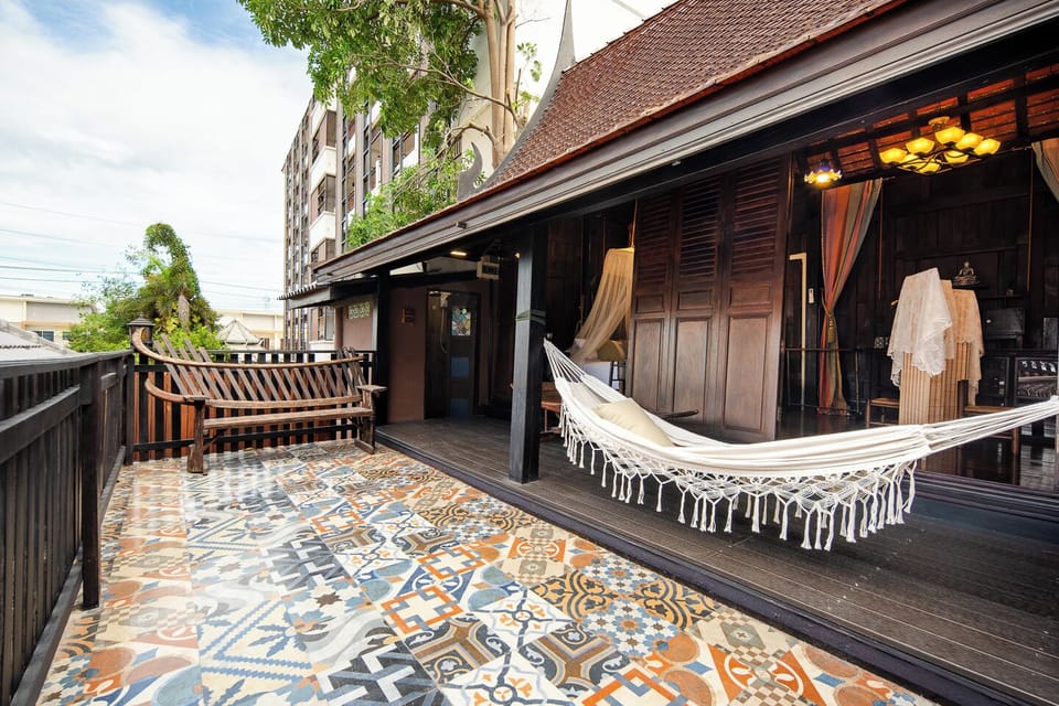 【Poolside Daybed】Under the house, a traditional cushioned daybed faces the pool and garden. It sleeps one more guest at night, and by day it is the best seat for watching the swimmers.