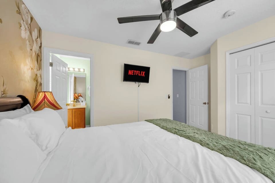 Warm bedroom w/ floral mural, TV & a ceiling fan — comfortable & quietly stylish.