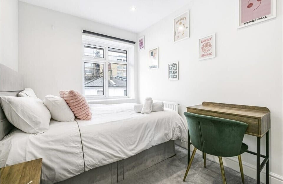 Bright bedroom with soft bedding, wall art, and a desk by the window