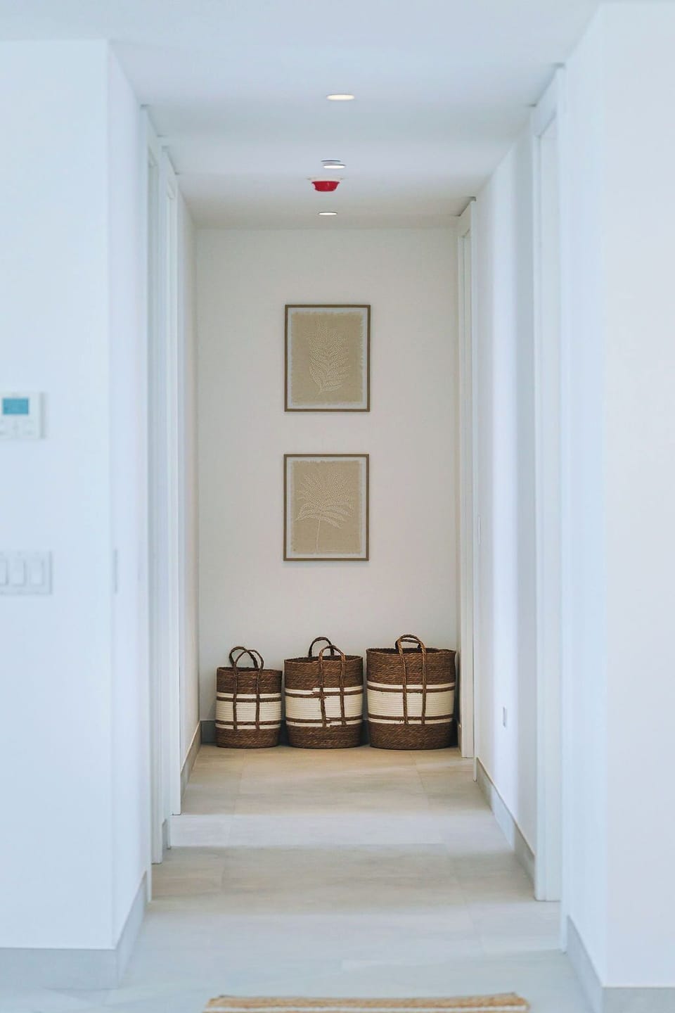 Bright hallway with natural woven storage baskets and coastal artwork providing functional organization for your beach essentials.