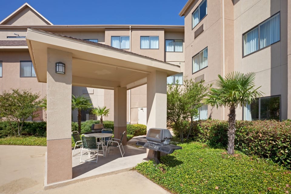 Covered outdoor seating area with table, chairs, and BBQ grill.