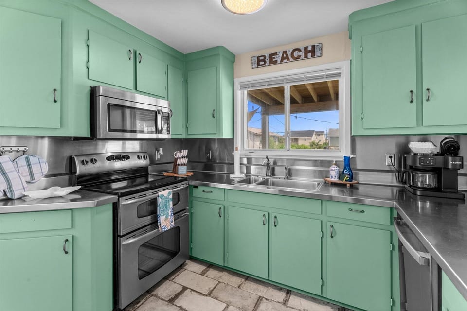 Well-equipped kitchen showcasing stainless steel range, microwave, spacious countertops, and abundant cabinet storage for vacation meal preparation.