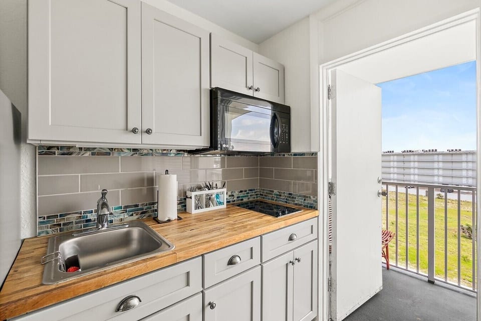 Kitchenette with simple meal prep space and access toward the private balcony.