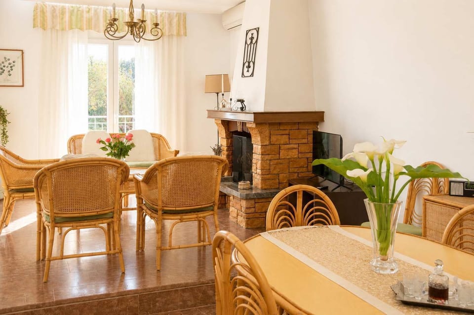 Gather with family and friends in the living area, featuring comfortable seating, warm décor, and a traditional fireplace. Large windows fill the room with natural light, creating a bright and welcoming atmosphere