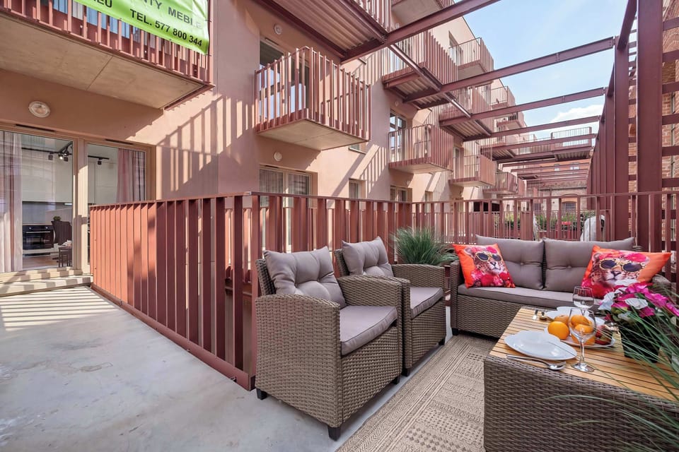Another view of the terrace showcases the layout of the outdoor wicker furniture set against the brick facades. The open-air design allows for a pleasant lounging experience.