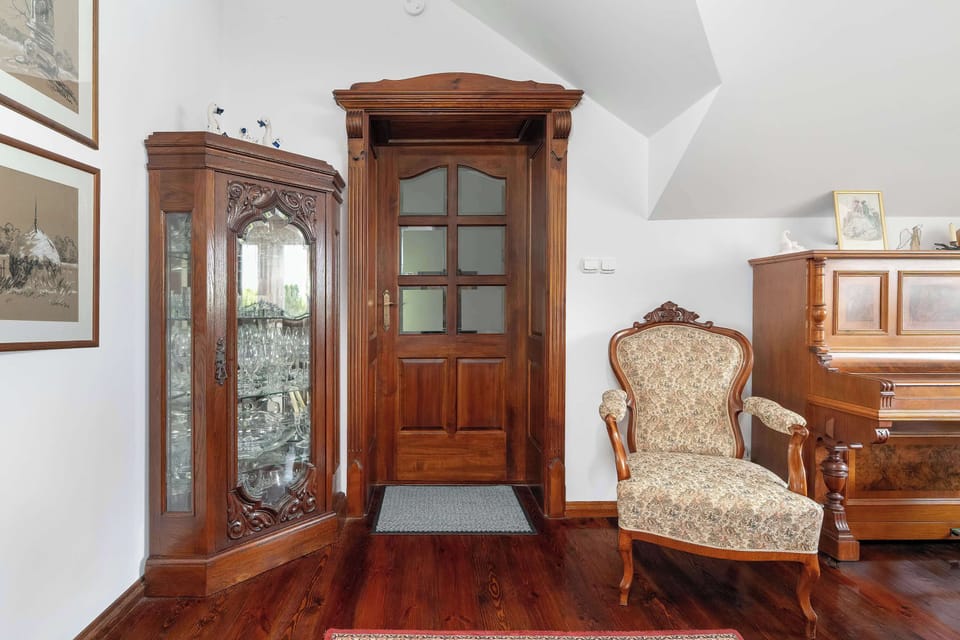 A formal seating corner featuring decorative armchairs, a large wooden display cabinet, and rich wood accents throughout the room.