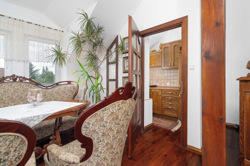 A dining room corner with carved wooden chairs, a decorative rug, and a doorway connecting to adjacent rooms.