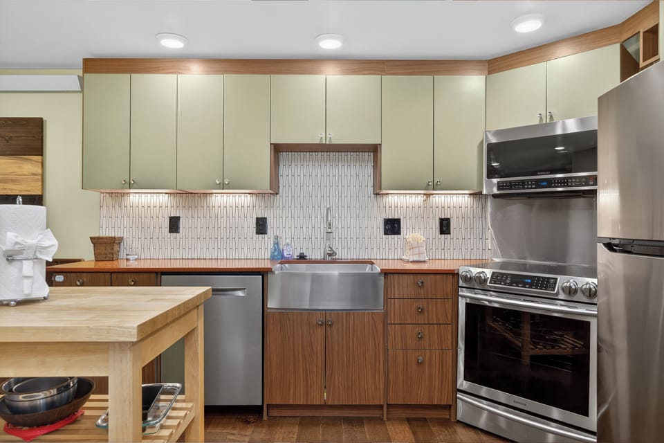 Step into your stylish, fully-equipped kitchen featuring modern stainless steel appliances, ample cabinetry, and a farmhouse sink—everything you need to whip up memorable meals during your stay.