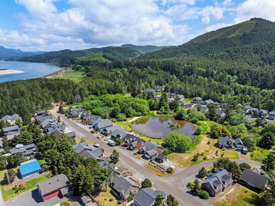 A coastal community nestled among forested mountains with tranquil waters and sandy beaches nearby, offering a serene natural setting.