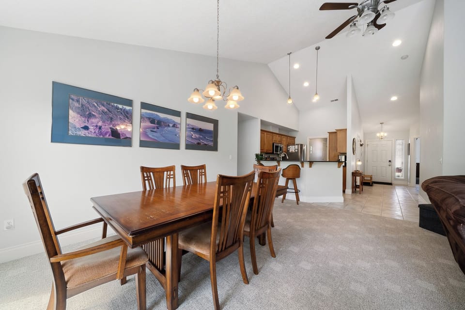 Gather around this welcoming dining table with seating for eight, perfect for your family meals and game nights. High ceilings, warm wood furniture, and open kitchen access create a spacious feel.