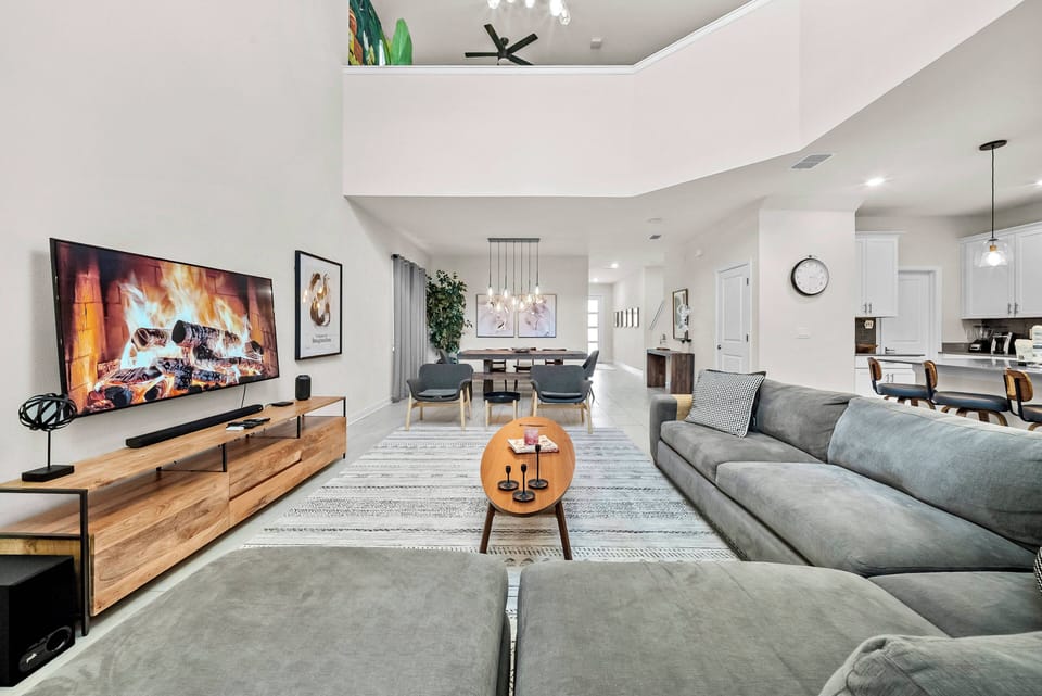 Enjoy a bright, spacious living area that seamlessly connects to the dining space. Unwind on the soft gray sectional by the cozy fireplace, surrounded by vibrant artwork that adds warmth and makes your stay truly inviting.