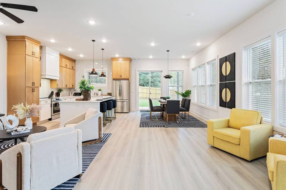 Open-concept living, dining, and kitchen area with floor-to-ceiling windows and direct access to the backyard patio. Perfect for entertaining or relaxing with family, surrounded by natural light and modern design details.