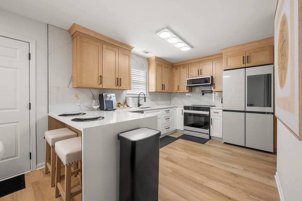 This open, modern kitchen offers the perfect blend of beauty and functionality—featuring quartz countertops, a smart fridge, full coffee setup, and bar seating for two. Ideal for home-cooked meals or casual mornings before exploring the city.