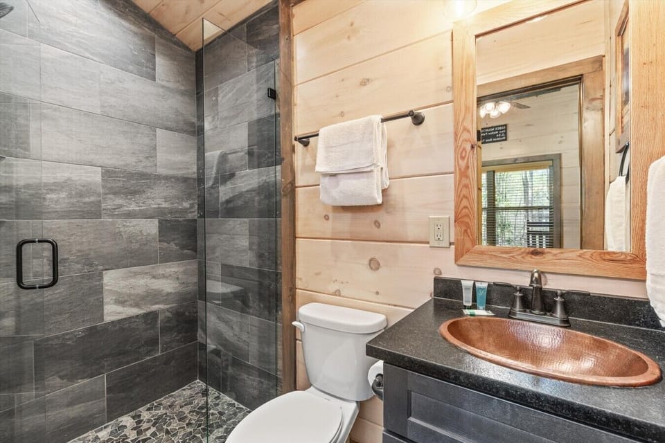 Bathroom with tiled shower and copper sink