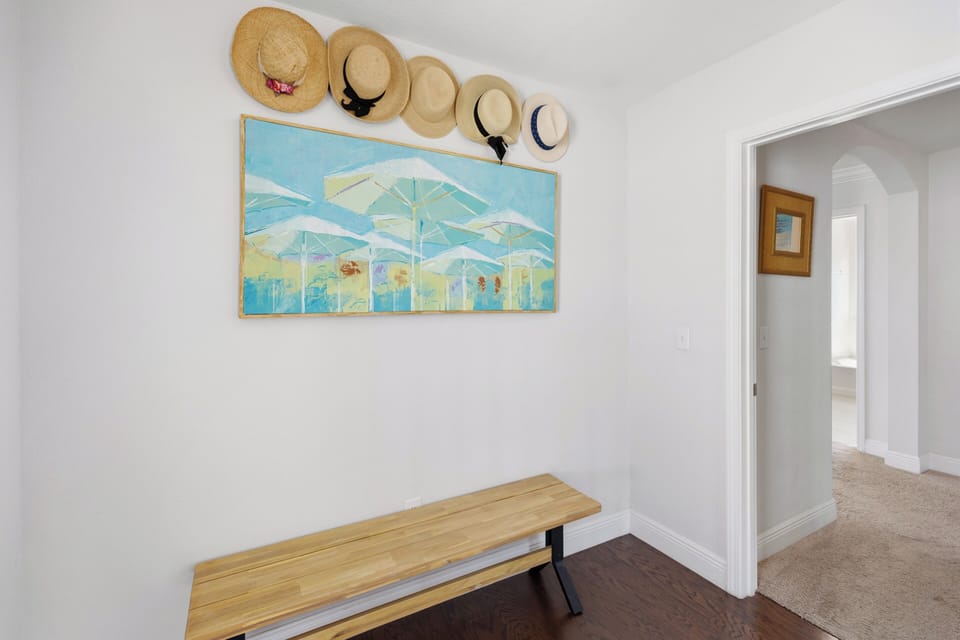 Step inside to find a welcoming entryway with coastal charm—beach hats and cheerful artwork set the tone for your relaxing escape.