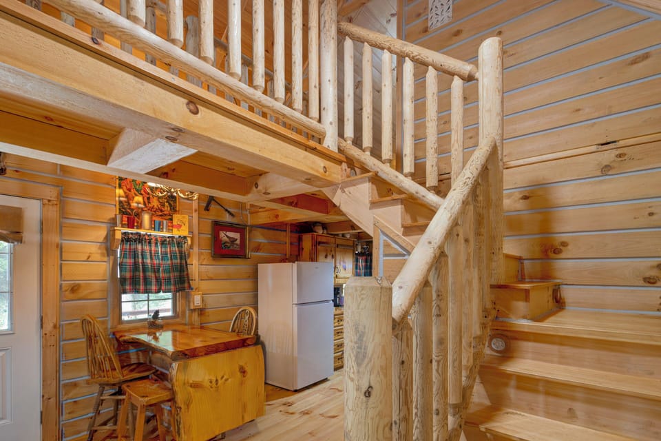 Rustic log cabin interior with loft stairs and a cozy dining nook