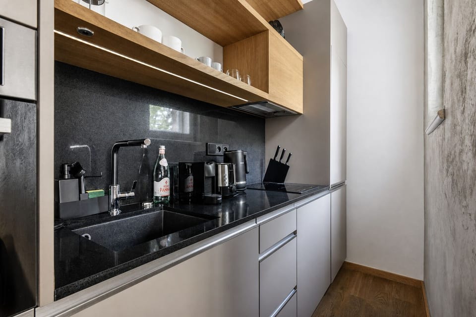 Sleek modern kitchen with black stone finishes and warm wood shelving